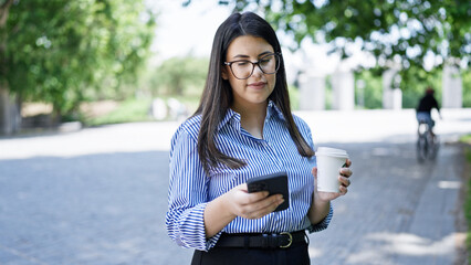 Poster - Young beautiful hispanic woman smiling happy using smartphone in the streets of Madrid