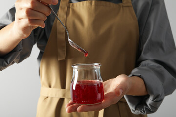 Sticker - Jar of fig jam and spoon in hands on white background