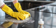 © Andres Mejia - Housekeeper wearing yellow gloves cleaning granite countertop in the kitchen
