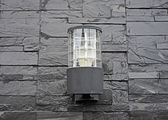 Wall Mural - An electric lamp is installed on a black brick wall.