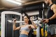 © Dusan Petkovic - Strong fit sportswoman doing shoulders exercises on machine at gym with her coach.