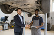 © sofiko14 - Businessman in formal attire shaking hands with mechanic in garage. Car on lift in background. Concept of business, partnership, service, and automotive industry.