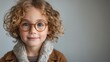 © Tetiana - A cheerful child with curly hair and glasses looks happily at the camera while indoors
