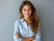 © Pixel Mind - A young woman stands with a confident smile, arms crossed, in front of a gray wall