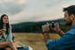 © La Famiglia - Boyfriend taking pictures of his girlfriend next to their car during a road trip on the hills