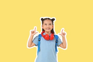 Sticker - Cute happy schoolgirl with headphones pointing at something on yellow background