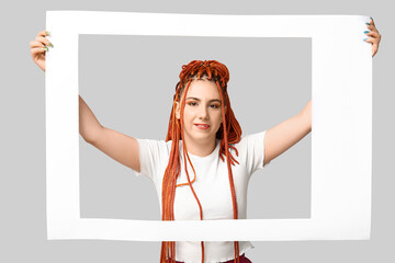 Wall Mural - Portrait of pretty young woman with dreadlocks and photo frame on grey background