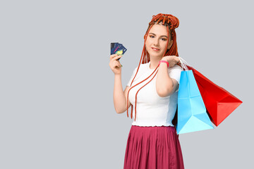 Wall Mural - Portrait of pretty young woman with dreadlocks, shopping bags and credit cards on grey background