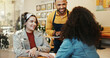 © PeakPoints/peopleimages.com - Coffee shop, women and waiter order with tablet, conversation and customer service at restaurant. Barista, staff and happy girl friends with smile and chat at diner with employee helping with tech