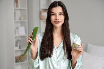 Poster - Beautiful young happy woman with plant leaf and jar of aloe vera gel in bedroom