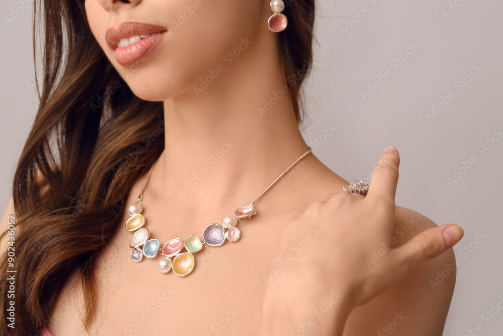 Beautiful woman with jewelry on grey background