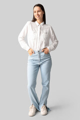 Poster - Beautiful young woman in stylish jeans on grey background