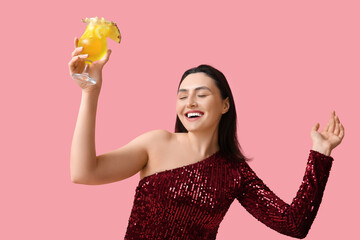 Wall Mural - Happy young woman with glass of tasty cocktail on pink background