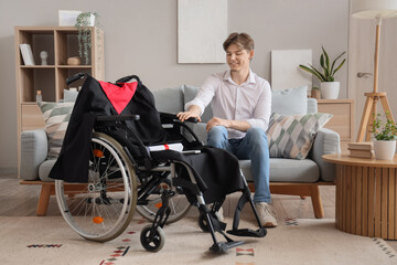 Wall Mural - Male graduate with wheelchair sitting on sofa at home