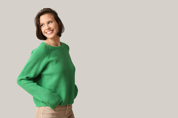 Sticker - Beautiful young woman in stylish green sweater on grey background