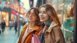 © chutikan - Two happy young women looking at store window while holding shopping bags near shopping mall