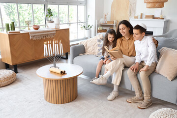 Poster - Happy Jewish mother with her little children reading book on sofa at home