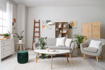 Poster - Interior of light living room with wooden ladder, sofa and armchair