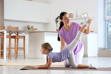 Canvas Print - Sporty mother with her little daughter training in kitchen