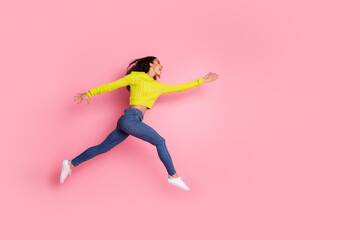 Wall Mural - Full length photo of sporty youth funny girl wearing green sweater and jeans jumping catching object in air isolated on pink color background