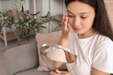 Poster - Young Asian woman with mirror putting in contact lenses in bathroom, closeup