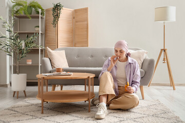 Wall Mural - Young woman after chemotherapy with bottle of weed and joint at home