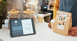© PeakPoints/peopleimages.com - Small business, tablet and payment with person in cafe, customer bill and online processing with digital app. Cafeteria, paper bag and screen interface with server staff, fintech and coffee shop sale