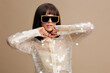 © SHOTPRIME STUDIO - Woman, sequinned shirt, sunglasses a woman in a shimmering sequinned shirt and trendy sunglasses, posing confidently with her hands on her head, while looking directly at the camera, exuding glamour