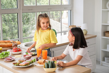 Wall Mural - Little girls with sausages making toasts in kitchen