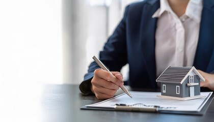 A professional signing a document with a model house, representing real estate investment and property management.