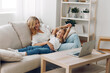 © SHOTPRIME STUDIO - Mother and child bonding on the couch while learning together using a laptop in a cozy living room setting