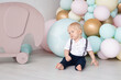 © Marharyta - Cute boy at home on his first birthday dressed in a suit with trousers on pull-ups and a shirt against the background of colorful balloons and a toy elephant. Family and childhood concept, holiday