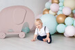 © Marharyta - Little boy at home on his first birthday dressed in a suit with trousers on pull-ups and a shirt against the background of colorful balloons and a toy elephant. Family and childhood concept, holiday