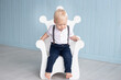 © Marharyta - Little boy at home on his first birthday sits on a throne-shaped chair, dressed in a suit with trousers on pull-ups and a shirt. Family and childhood concept, holiday