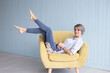 © Marharyta - Woman with short hair in armchair at home. Portrait of comfortable woman in shirt and jeans relaxing on armchair. Portrait of beautiful girl smiling and relaxing