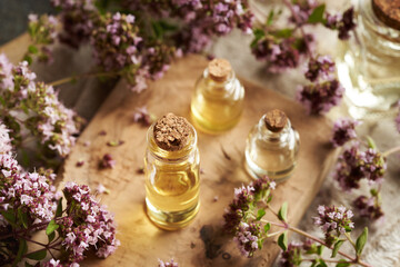 Wall Mural - Glass bottles of aromatherapy essential oil with fresh blooming oregano twigs