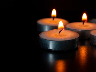 Candles shining on dark background with customizable space for text of message. Copy space concept