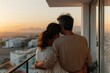 © Milos - A couple embraces and looks at the city skyline from their balcony during sunset, reflecting a moment of love and tranquility in a serene urban setting.