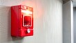 © Wanlop - Red handled fire alarm pull station mounted on a white wall with a bright red strobe light above it warning sign.