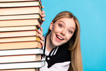 Sticker - Close up portrait of cheerful glad clever girl wear stylish clothes peek out book isolated on blue color background