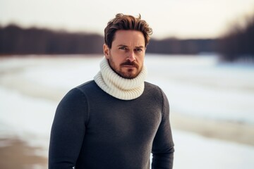 Sticker - Portrait of a glad man in his 30s wearing a classic turtleneck sweater over backdrop of a frozen winter lake