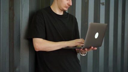 Freelancer on a gray background with a laptop in his hands.
Modern technologies.
Young programmer working at a laptop