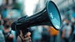 © svastix - A close-up image of a person holding a megaphone amidst a protest or public gathering, highlighting communication and advocacy in a dynamic outdoor environment.
