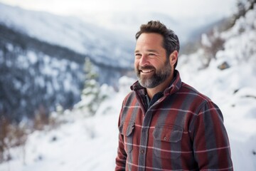 Canvas Print - Portrait of a grinning man in his 40s wearing a comfy flannel shirt isolated on pristine snowy mountain