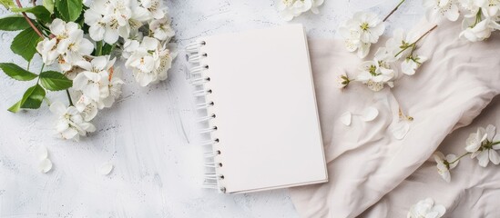 Poster - Styled photo featuring a white notebook with copy space image decorated with flowers on a light background