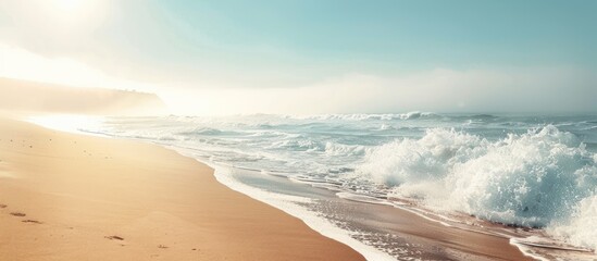 Poster - Misty morning sun shining above a sandy ocean shore with waves providing a clear view in the distance for a copy space image