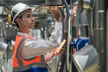 Engineers inspect gas and water pipes for power and cooling in industrial and building systems. workers in safety gear work seriously in oil and gas refining plant with pipes connecting to machinery.