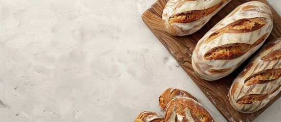 Poster - A high quality photo of a bakery display featuring golden rustic loaves of bread on a wooden board placed on a light background captured from above with a layout including copy space image