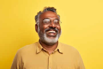 Canvas Print - Portrait of a content indian man in his 50s wearing a comfy flannel shirt on pastel yellow background