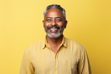 Canvas Print - Portrait of a content indian man in his 50s wearing a comfy flannel shirt isolated on pastel yellow background